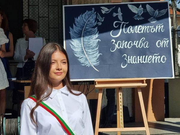 Ученичка пред дъска с надпис „Полетът започва от знанието"